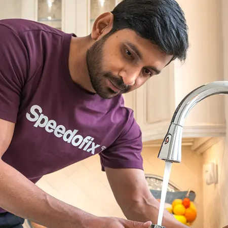 Plumber from Speedofix repairing a kitchen faucet leakage in an apartment at The Emirates Hills, Dubai.